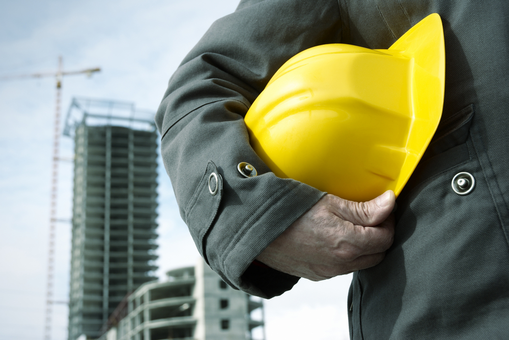 Engineer holding a helmet for workers security on background of building construction