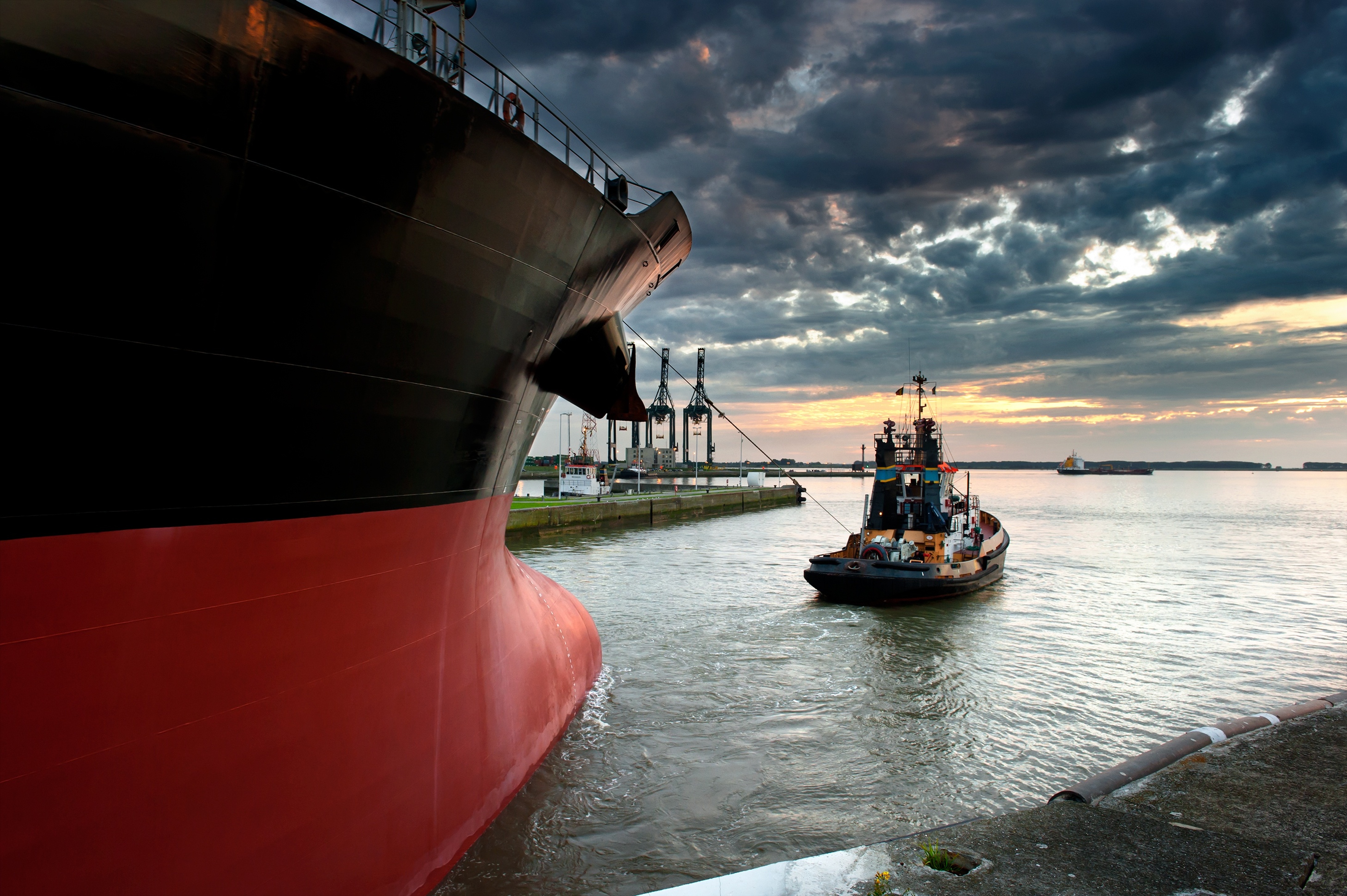 A tug boat guiding a large container ship out of a port