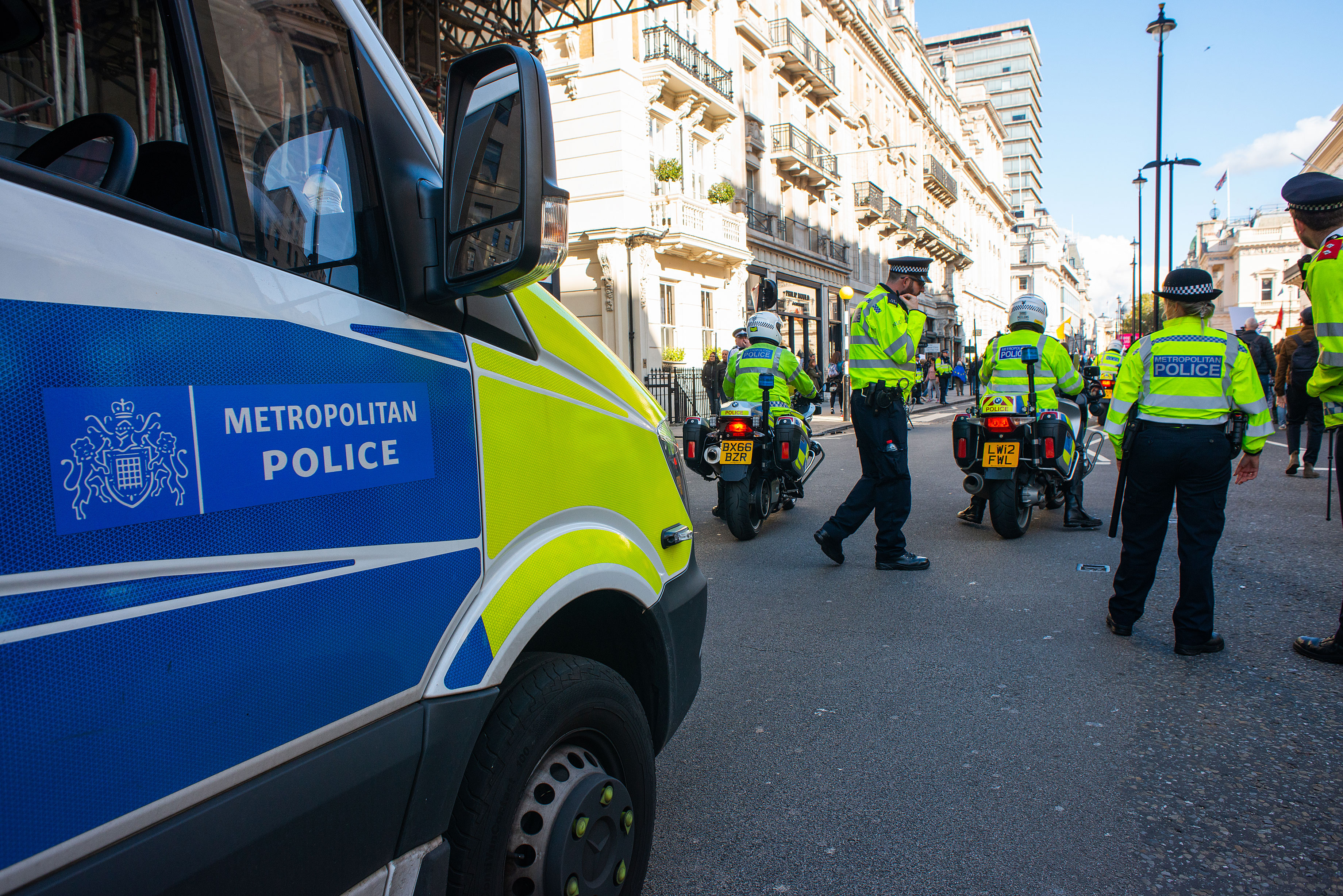 Police officers standing in a street with a police van in the foreground