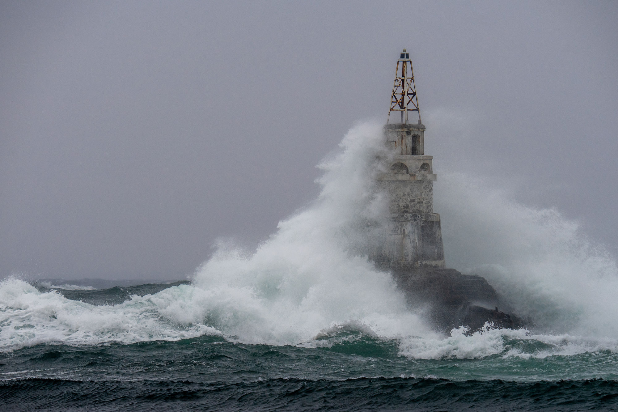Storm in a port, big wave hitting a lighthouse 